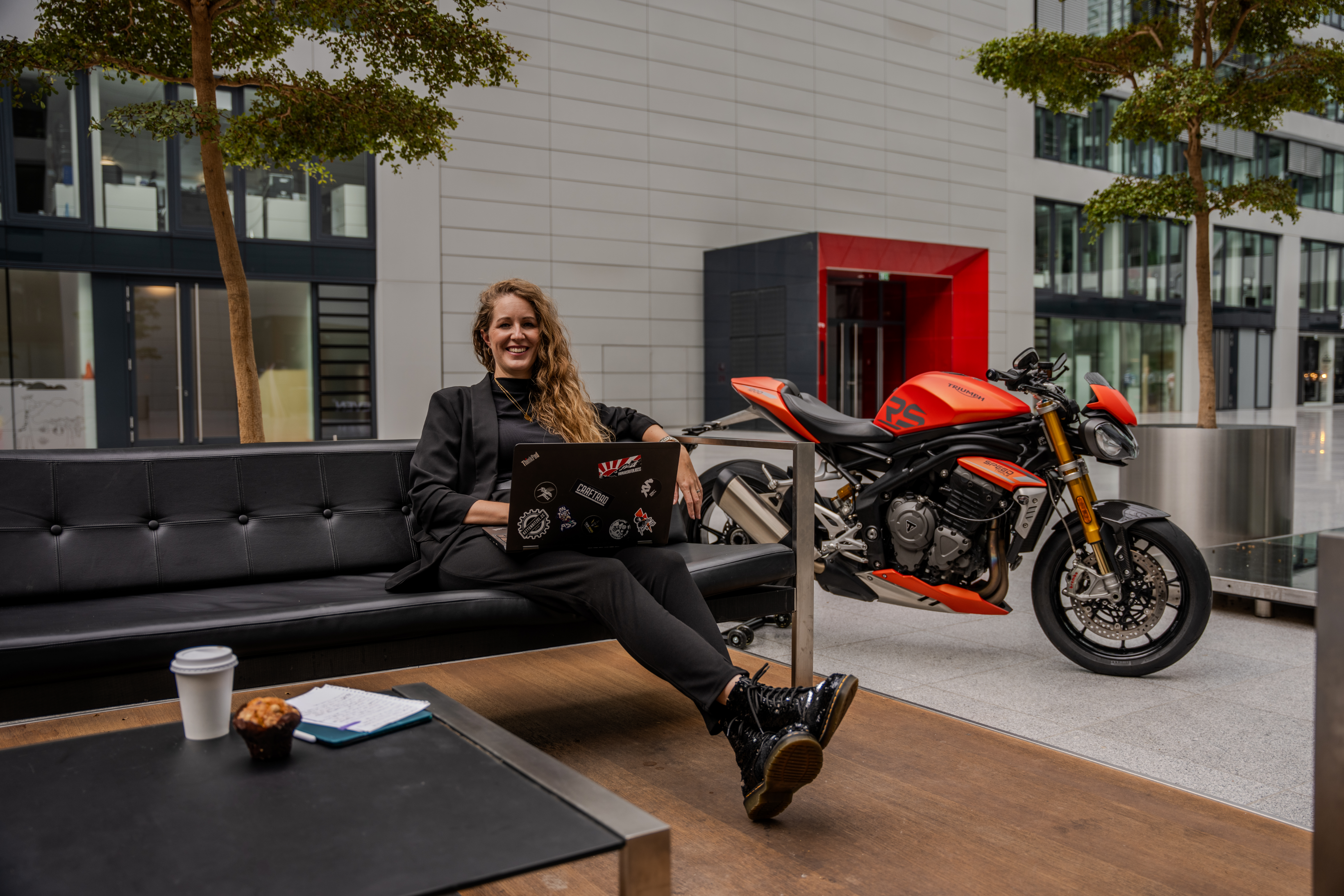 Sandra Bartel mit Laptop neben einer Triumph Speed Triple